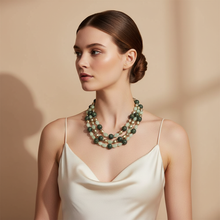 Load image into Gallery viewer, Woman wearing a green beaded necklace against a beige background