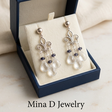 Load image into Gallery viewer, White topaz and iolite earrings in a navy jewelry box