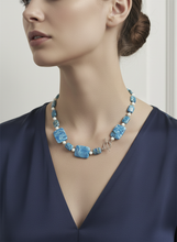 Load image into Gallery viewer, Woman wearing a blue necklace with a plain background
