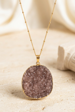 Load image into Gallery viewer, Brighter brown-purple druzy necklace editorial on pale travertine
