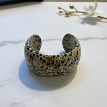 Load image into Gallery viewer, Dalmatian jasper cuff bracelet flat lay on marble
