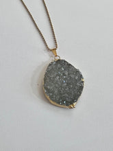 Load image into Gallery viewer, Silver-gray druzy teardrop pendant with gold-tone edging and bail shown on a chain
